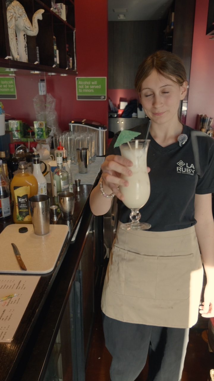 A bartender at La Ruby Thai holding a finished cocktail