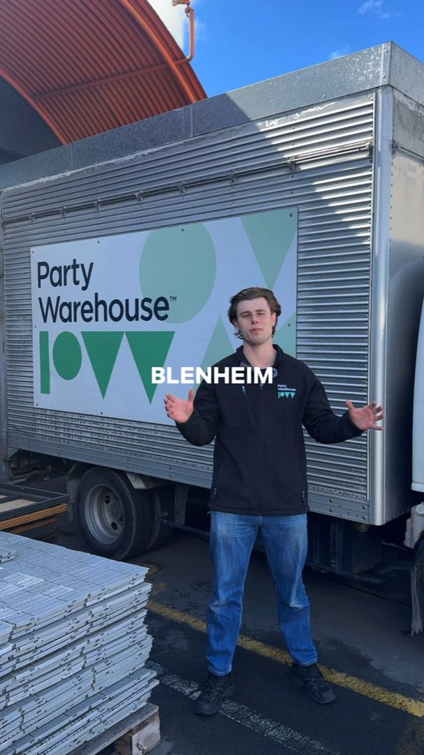 A presenter in front of a Party Warehouse delivery truck in Blenheim